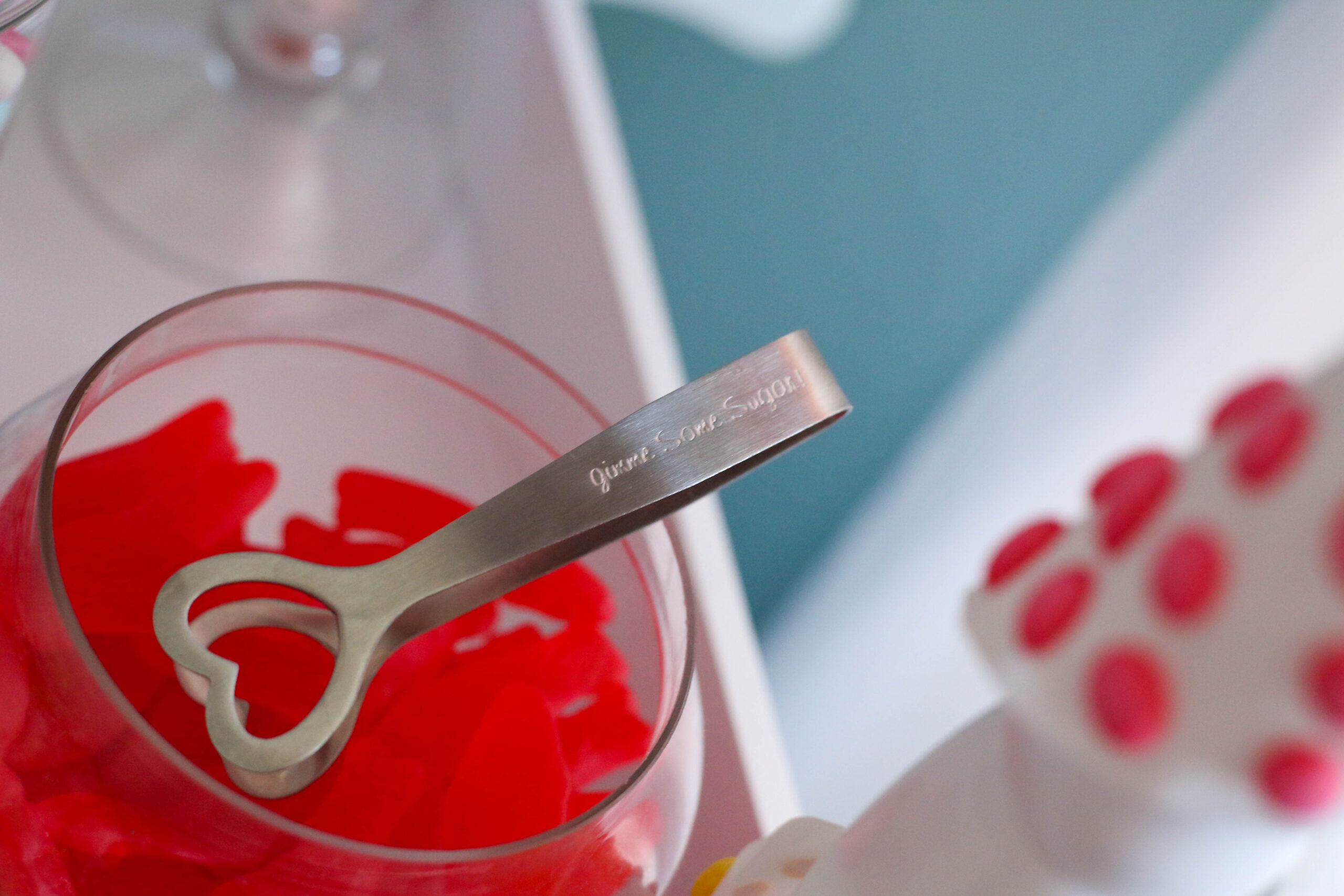 swedish fish candy in a glass candy jar with heart shaped tongs