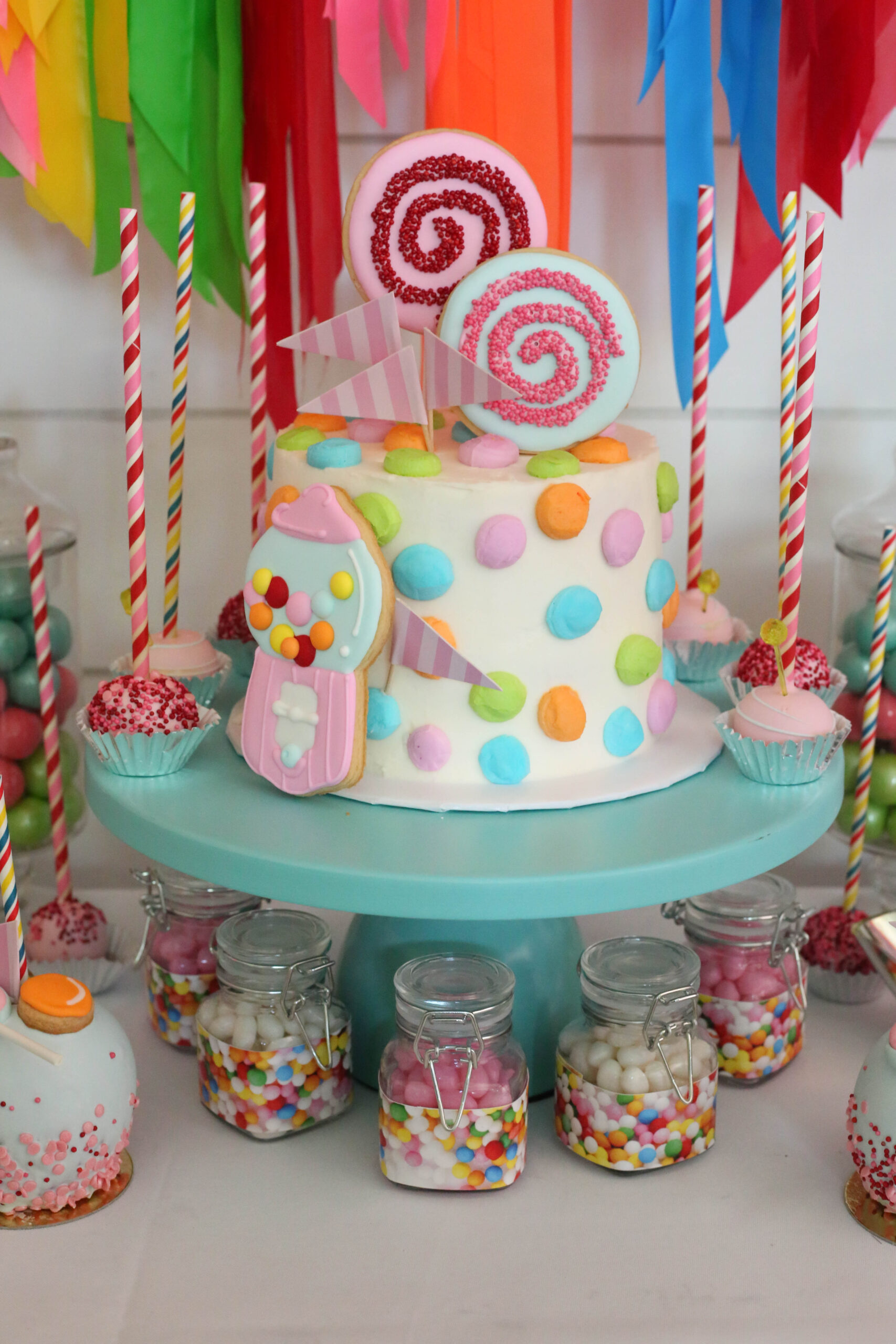 candy buttons cake and flag tape backdrop at a rainbow candy party